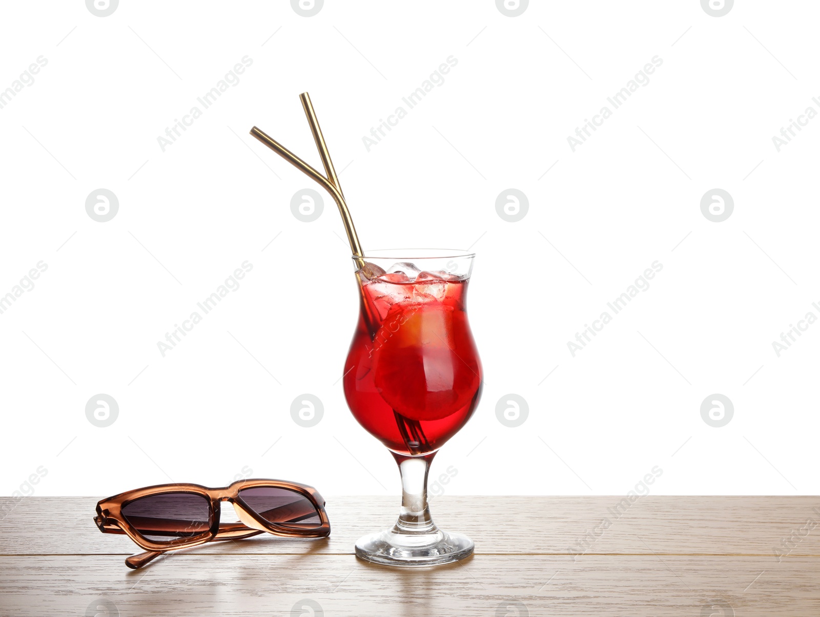 Photo of Glass of tasty refreshing drink, straws and sunglasses on wooden table against white background