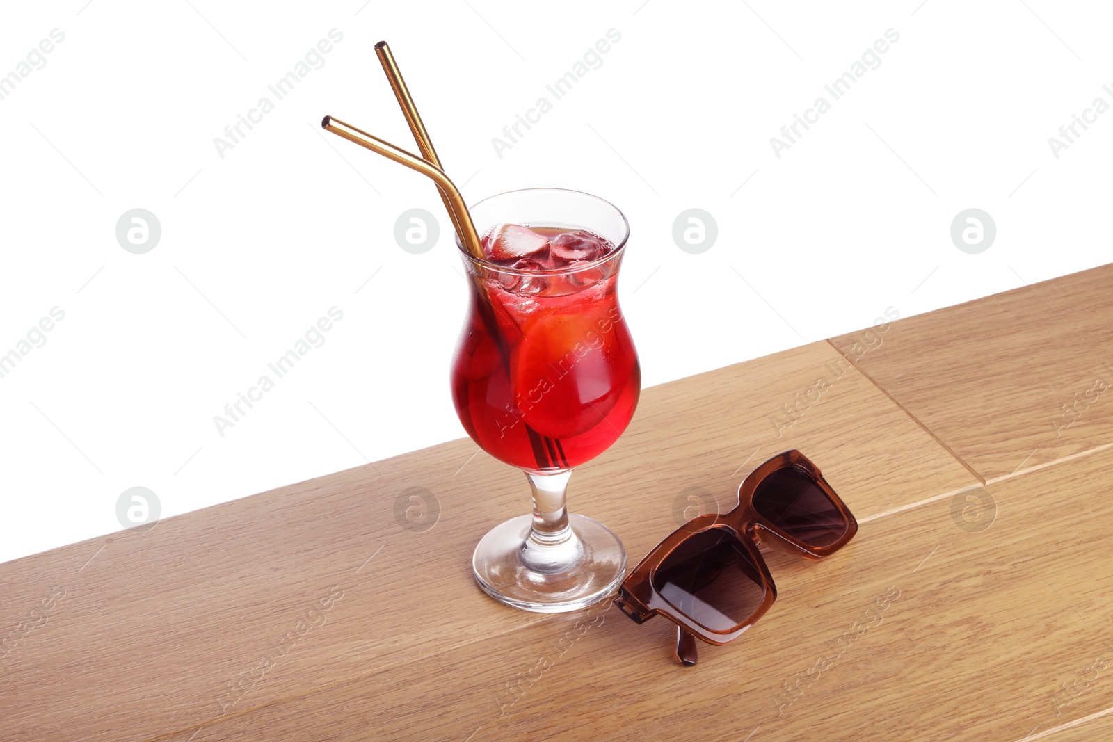 Photo of Glass of tasty refreshing drink, straws and sunglasses on wooden table against white background