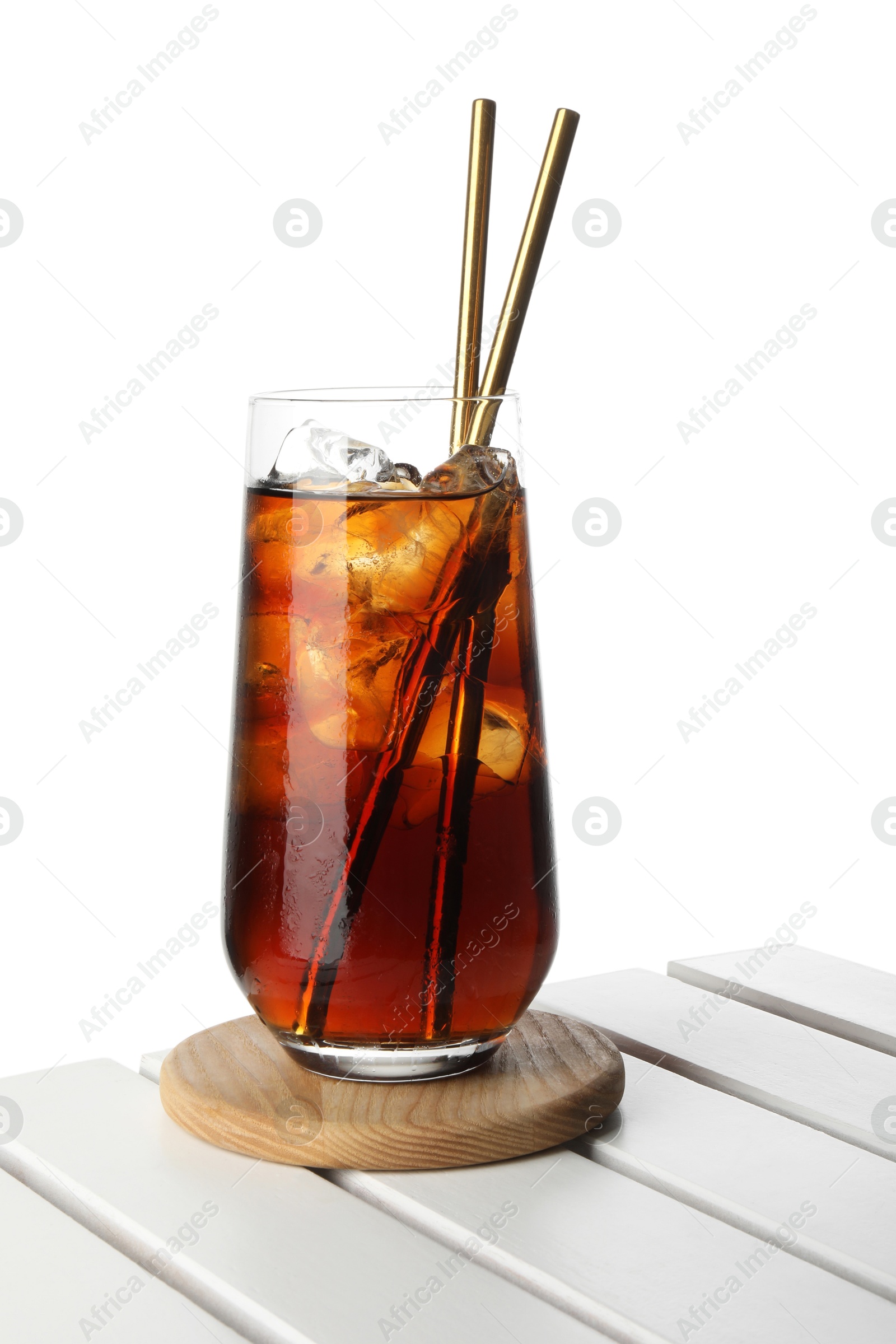 Photo of Glass of tasty refreshing drink and straws on wooden table against white background