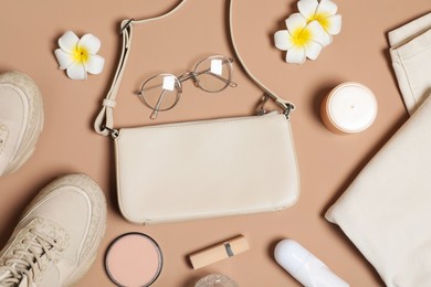 Photo of Stylish accessories and makeup products on brown background, flat lay