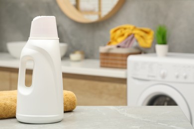 Photo of Laundry detergent and terry towel on light grey marble table in bathroom. Space for text