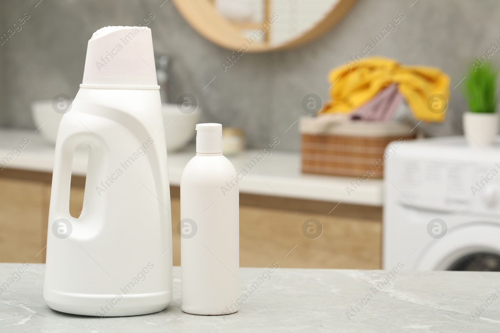 Photo of Laundry detergents on light grey marble table in bathroom. Space for text