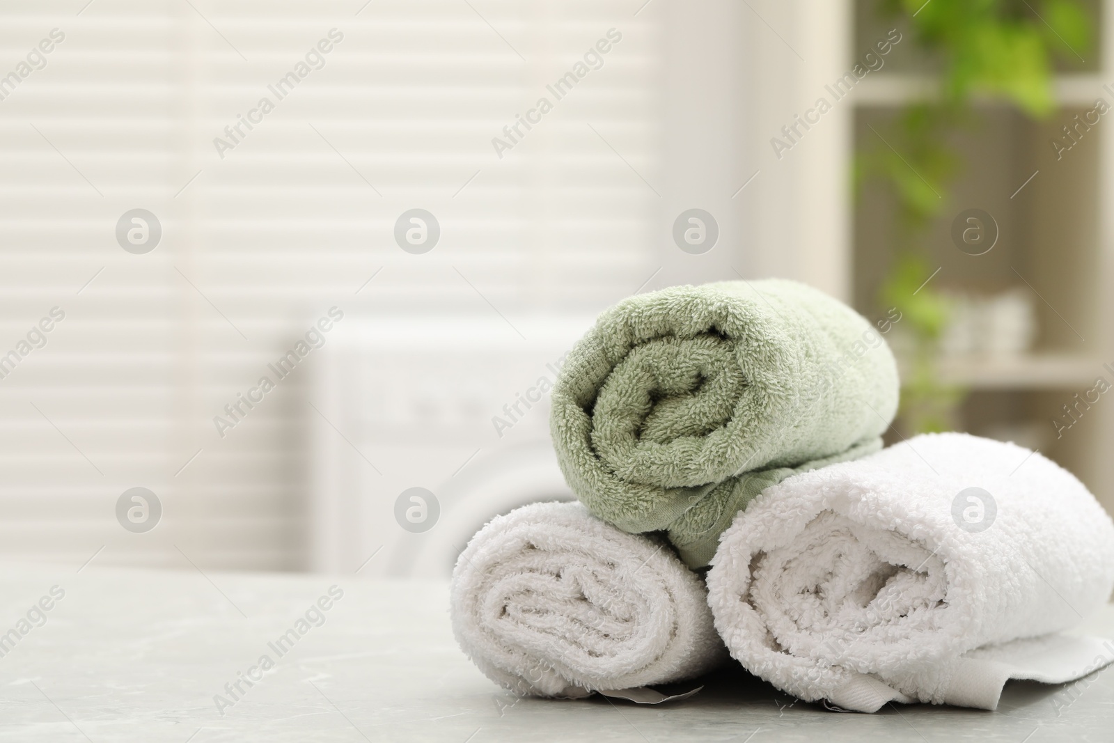 Photo of Rolled terry towels on light table in laundry room. Space for text