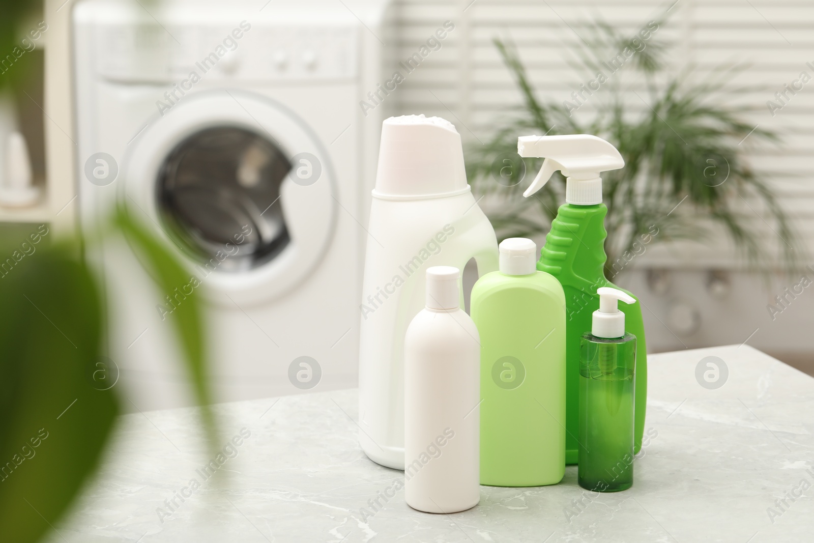 Photo of Different laundry detergents on light marble table in bathroom. Space for text