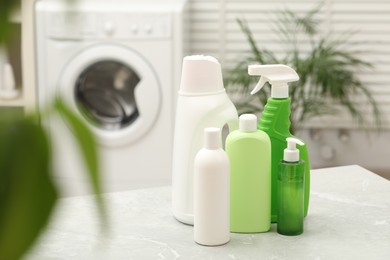 Photo of Different laundry detergents on light marble table in bathroom. Space for text