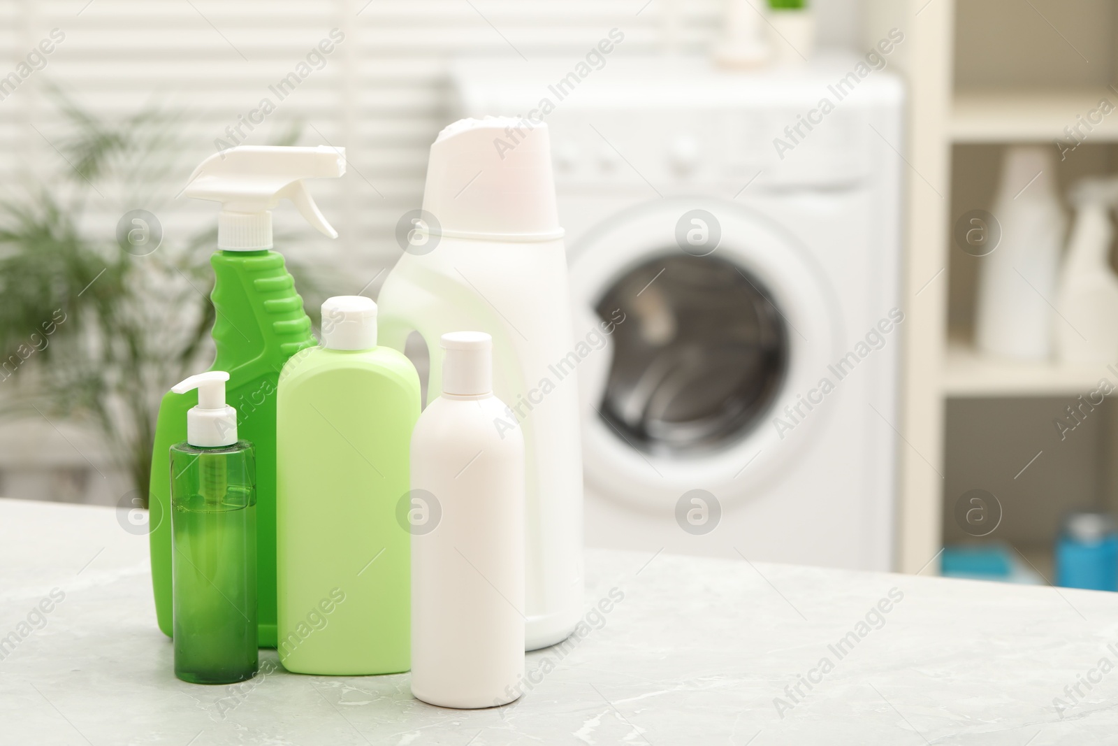 Photo of Different laundry detergents on light marble table in bathroom. Space for text