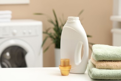 Photo of Laundry detergent and stacked terry towels on white table in bathroom. Space for text