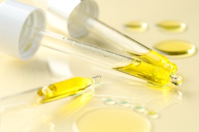 Photo of Cosmetic oil and pipettes on dark beige background, closeup