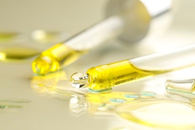 Photo of Cosmetic oil and pipettes on dark beige background, closeup