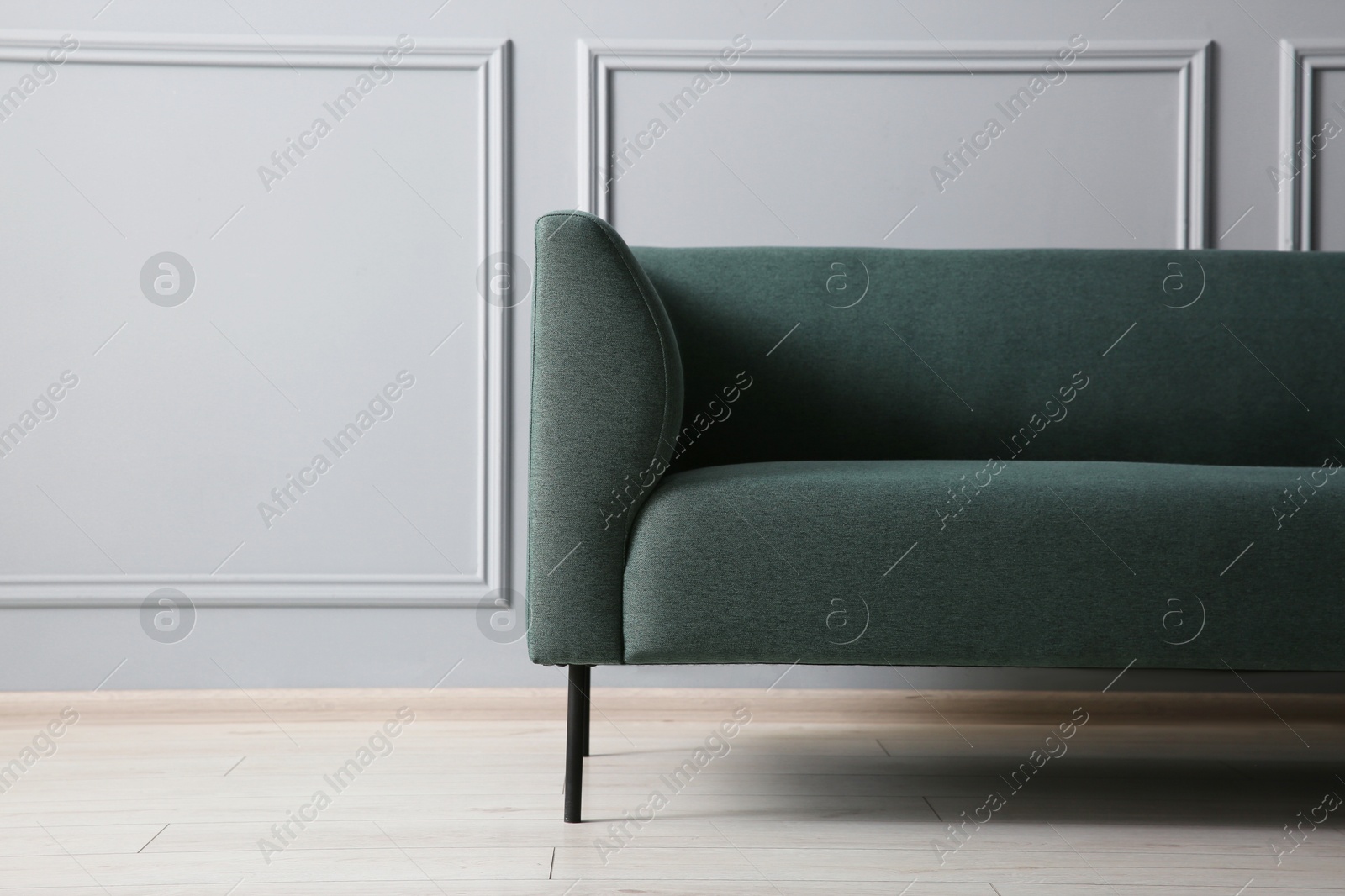 Photo of One stylish sofa near grey wall, space for text