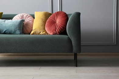 Photo of Stylish sofa with cushions near grey wall