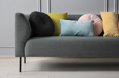 Photo of Stylish sofa with cushions near grey wall