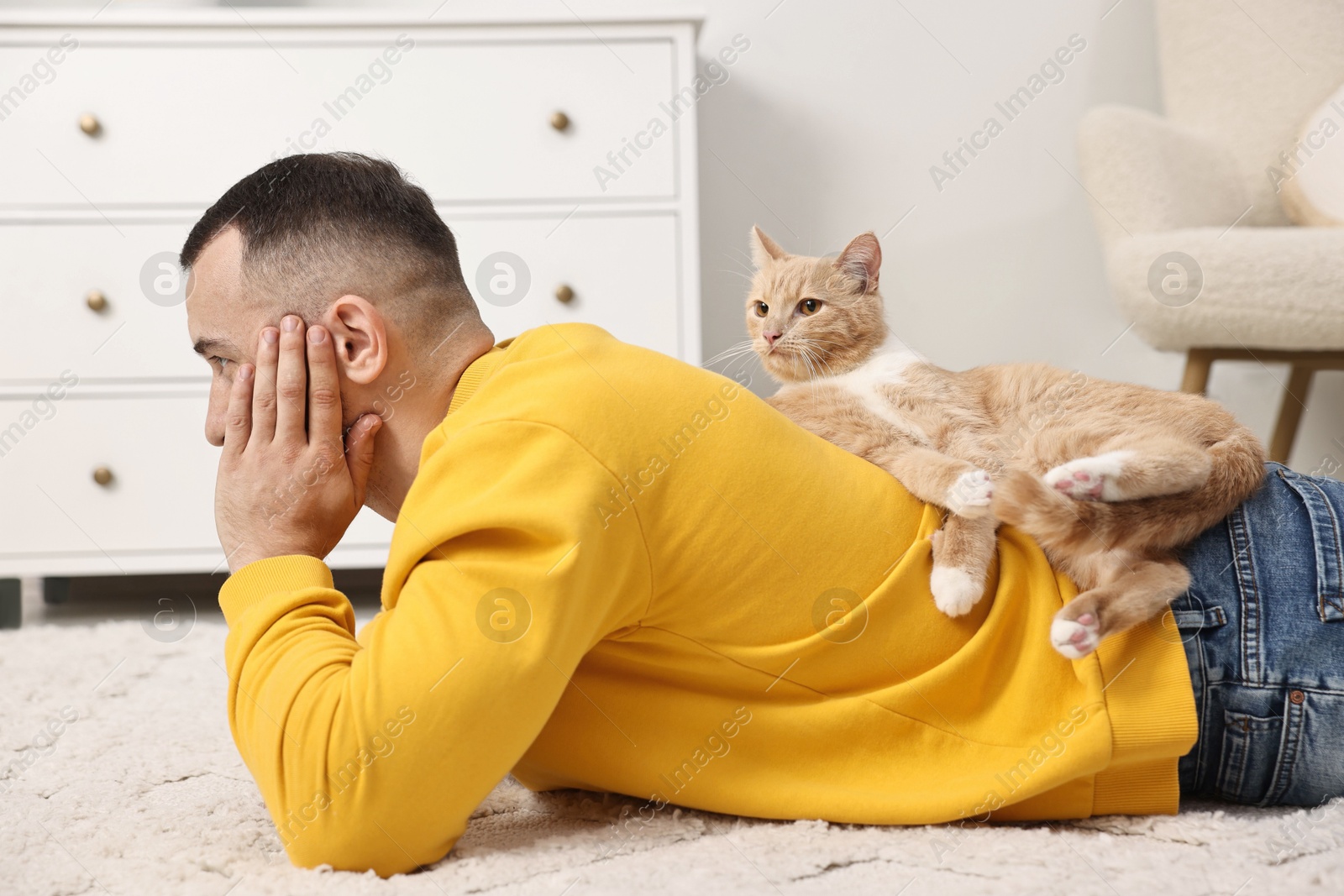 Photo of Man with cute ginger cat lying on floor at home