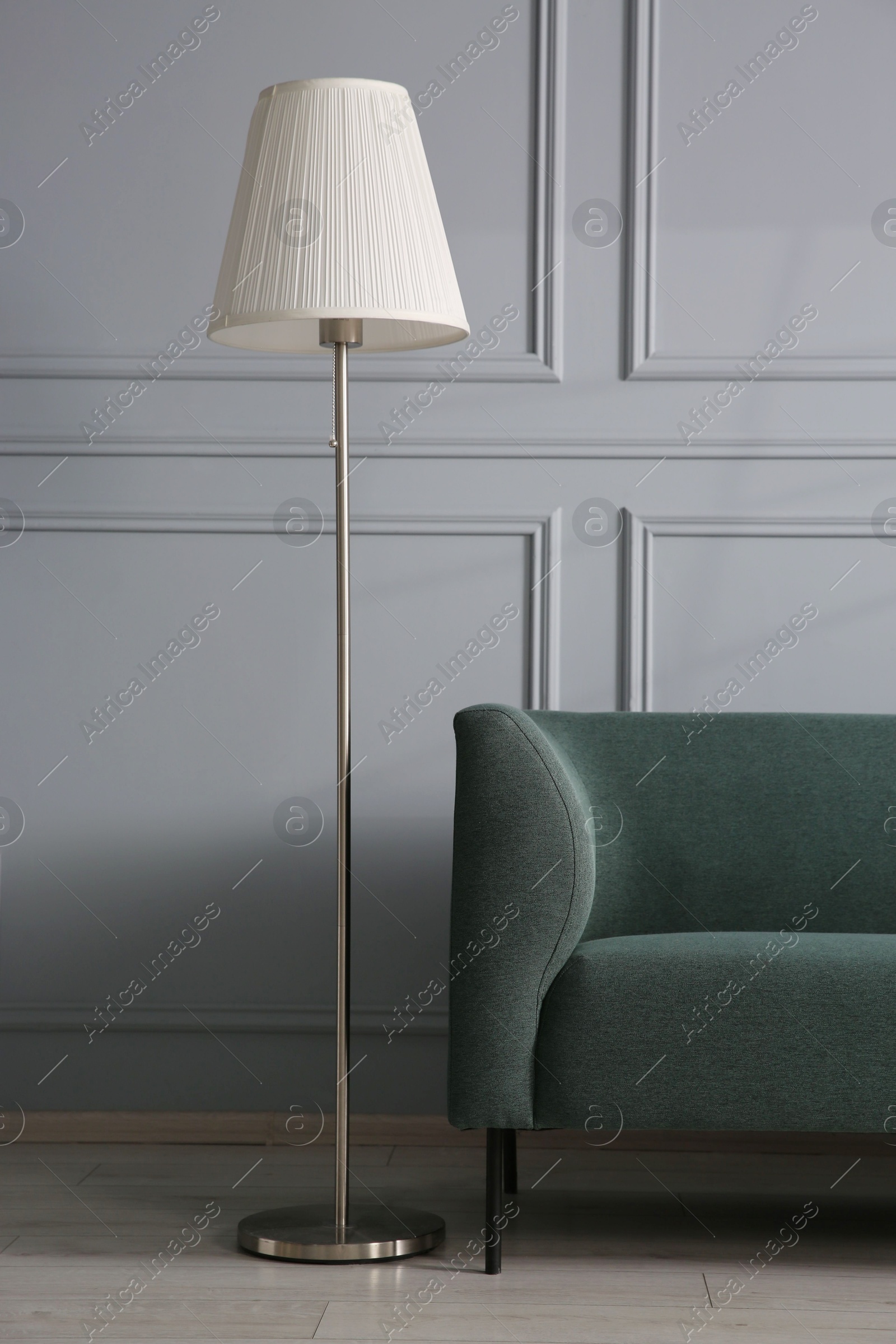 Photo of Comfortable sofa and lamp near grey wall in room