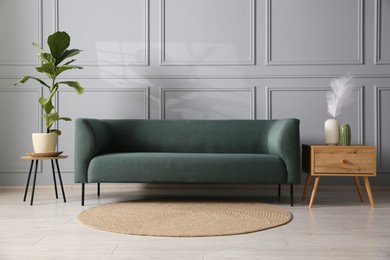 Photo of Comfortable sofa, houseplant and side table near grey wall in room