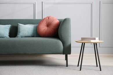 Photo of Comfortable sofa and side table near grey wall in room