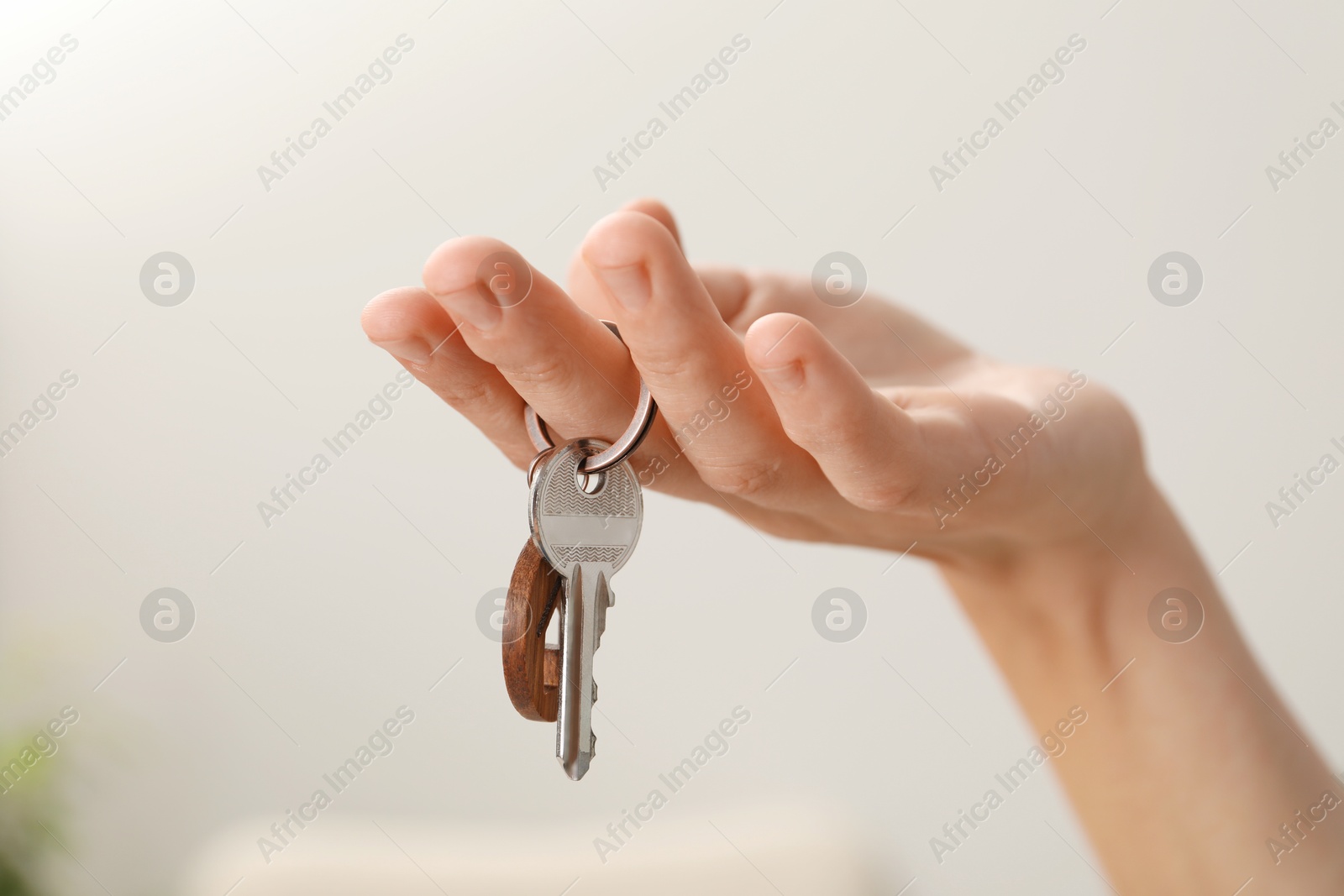 Photo of Woman holding key with house shaped keychain indoors, closeup