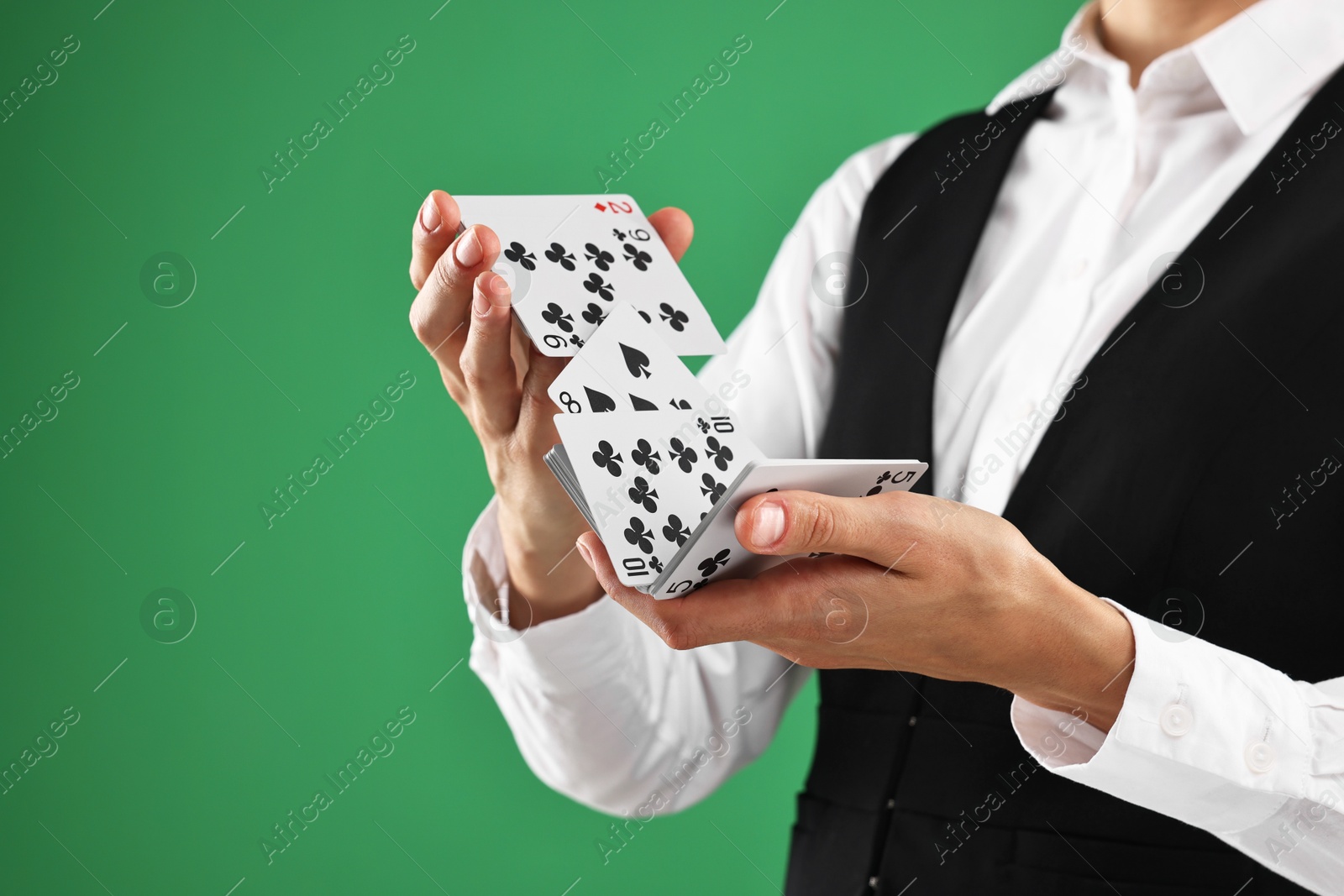 Photo of Professional croupier shuffling cards on green background, closeup