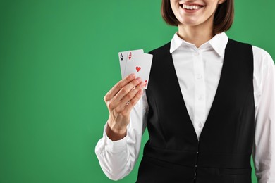 Photo of Croupier with playing cards on green background, closeup. Space for text