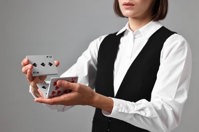 Professional croupier shuffling cards on grey background, closeup