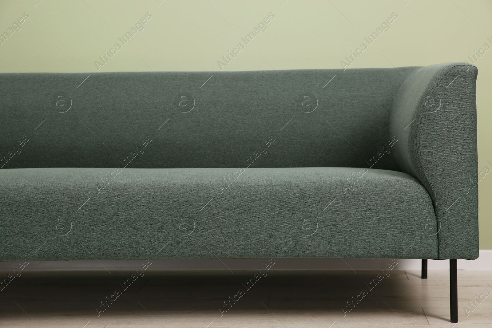 Photo of One stylish sofa near green wall indoors