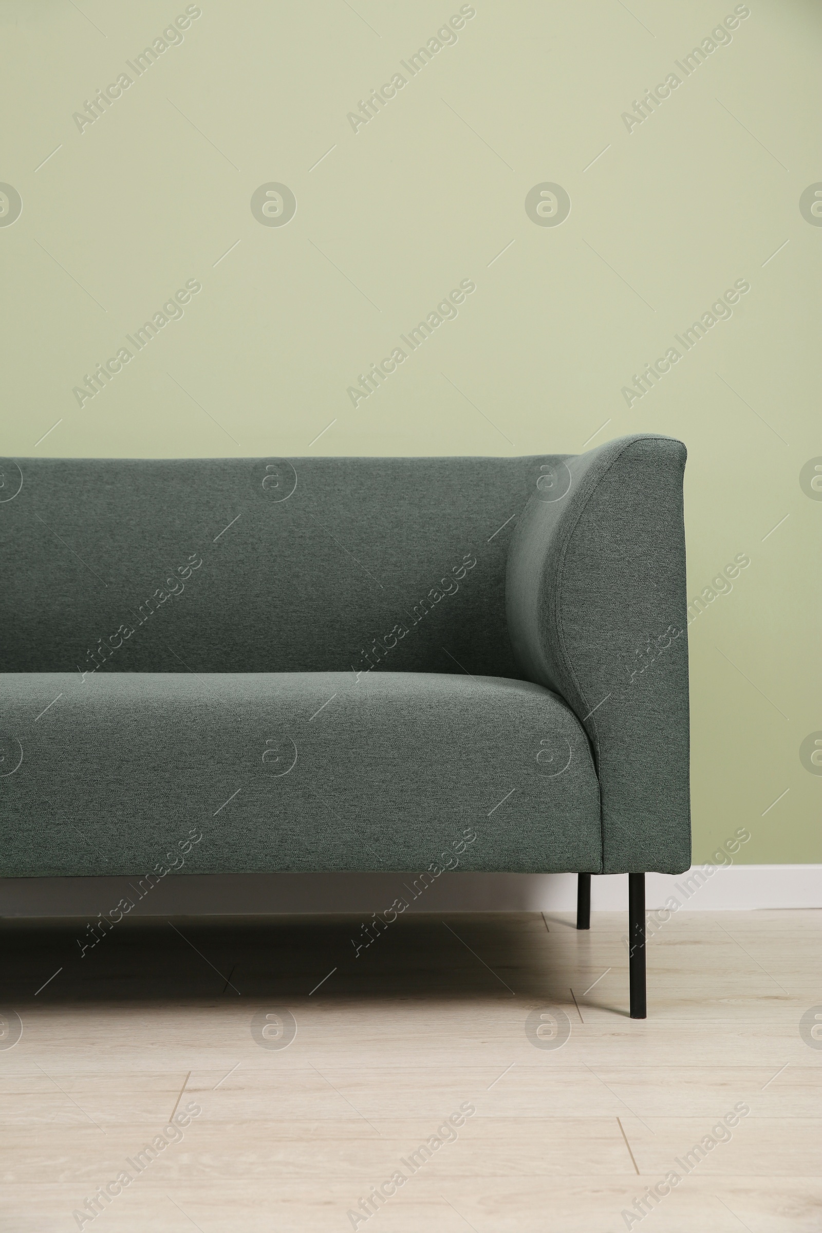 Photo of One stylish sofa near green wall indoors