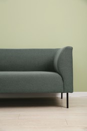 Photo of One stylish sofa near green wall indoors