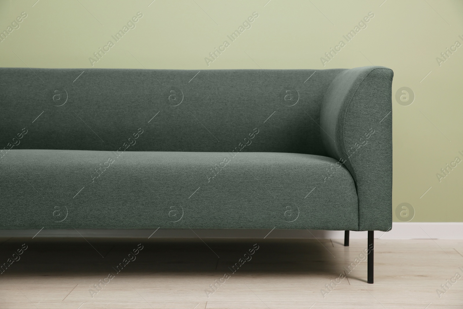 Photo of One stylish sofa near green wall indoors