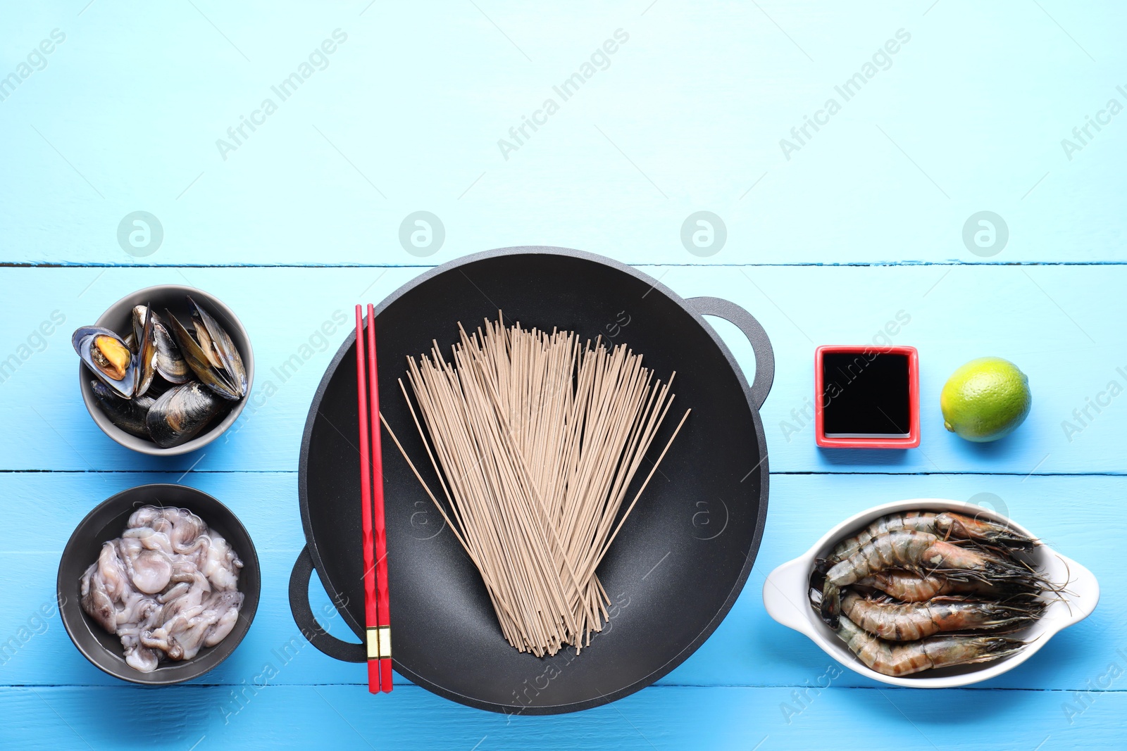 Photo of Different ingredients for wok on light blue wooden table, flat lay