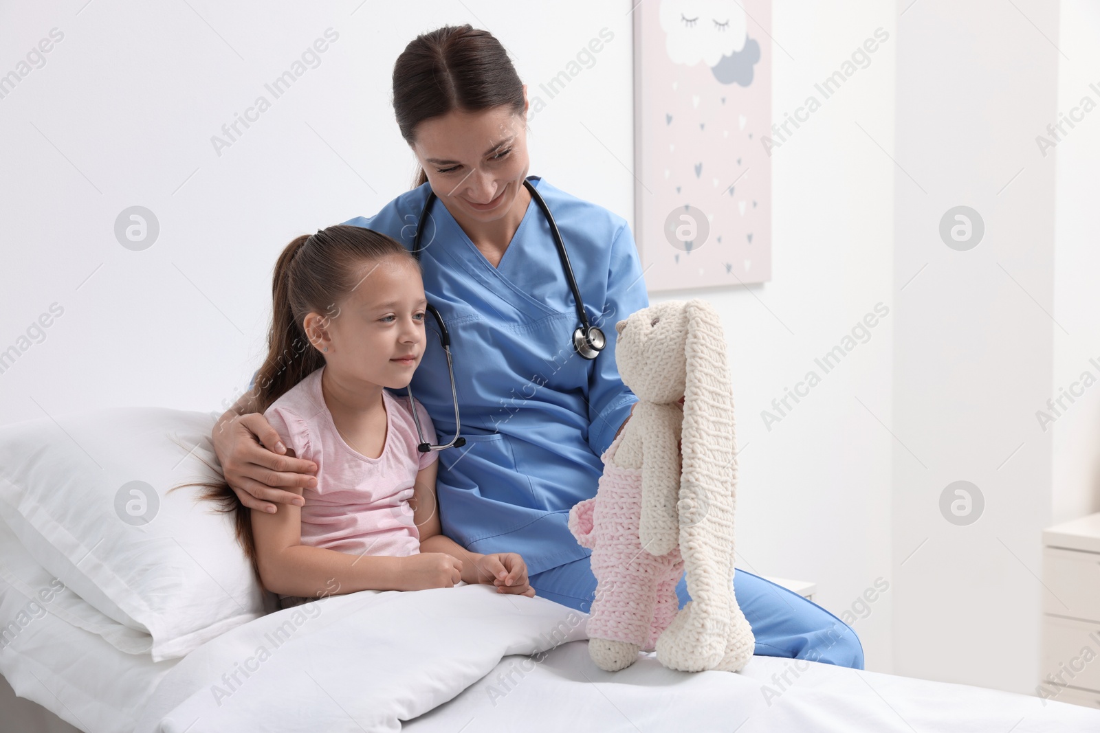 Photo of Doctor examining little girl on bed at hospital