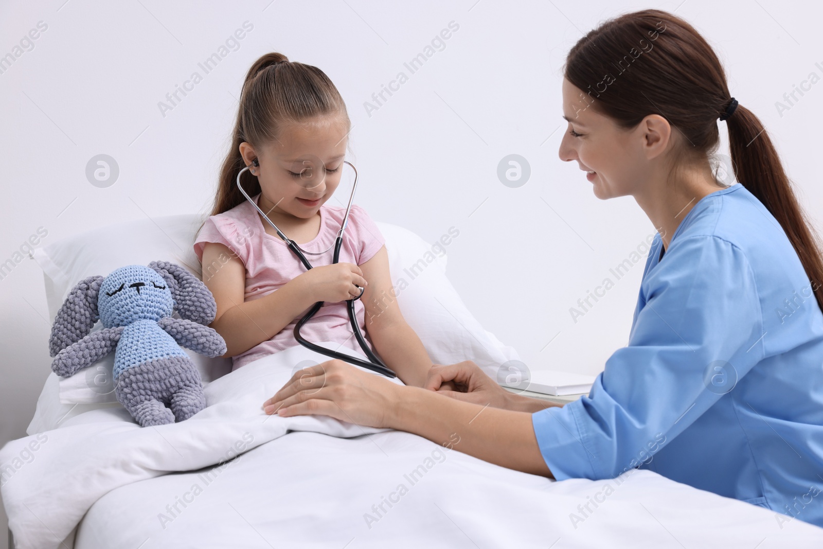 Photo of Doctor examining little girl on bed at hospital