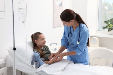 Doctor examining little girl on bed at hospital