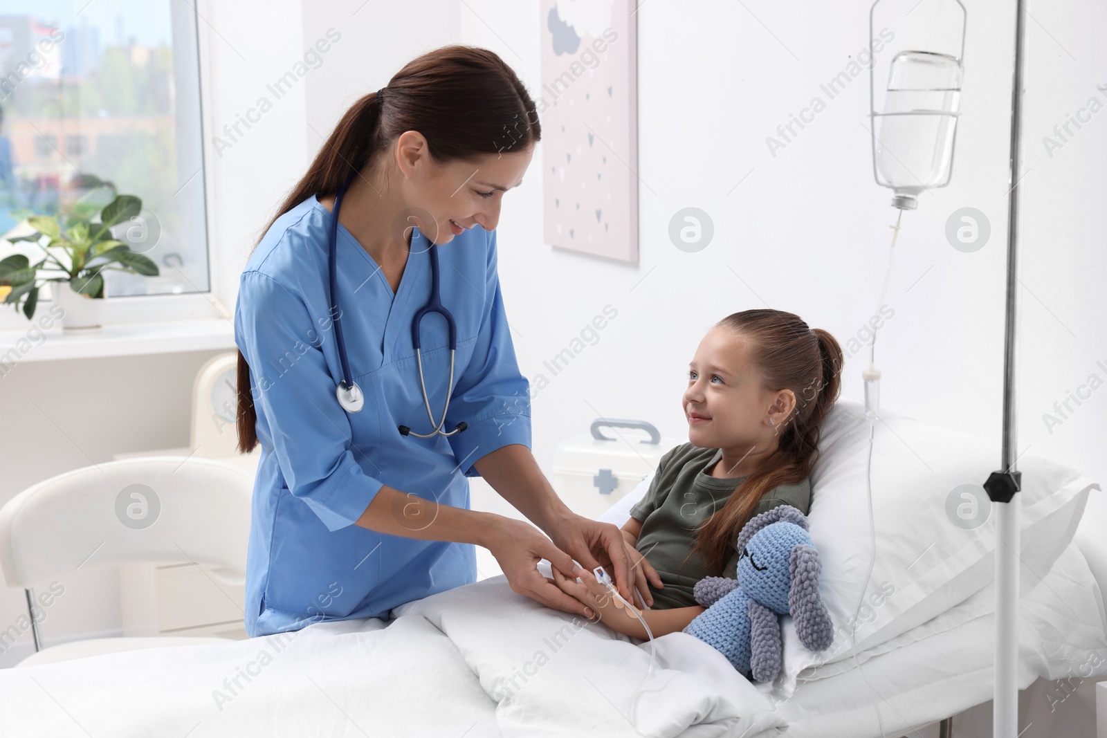 Photo of Doctor examining little girl on bed at hospital