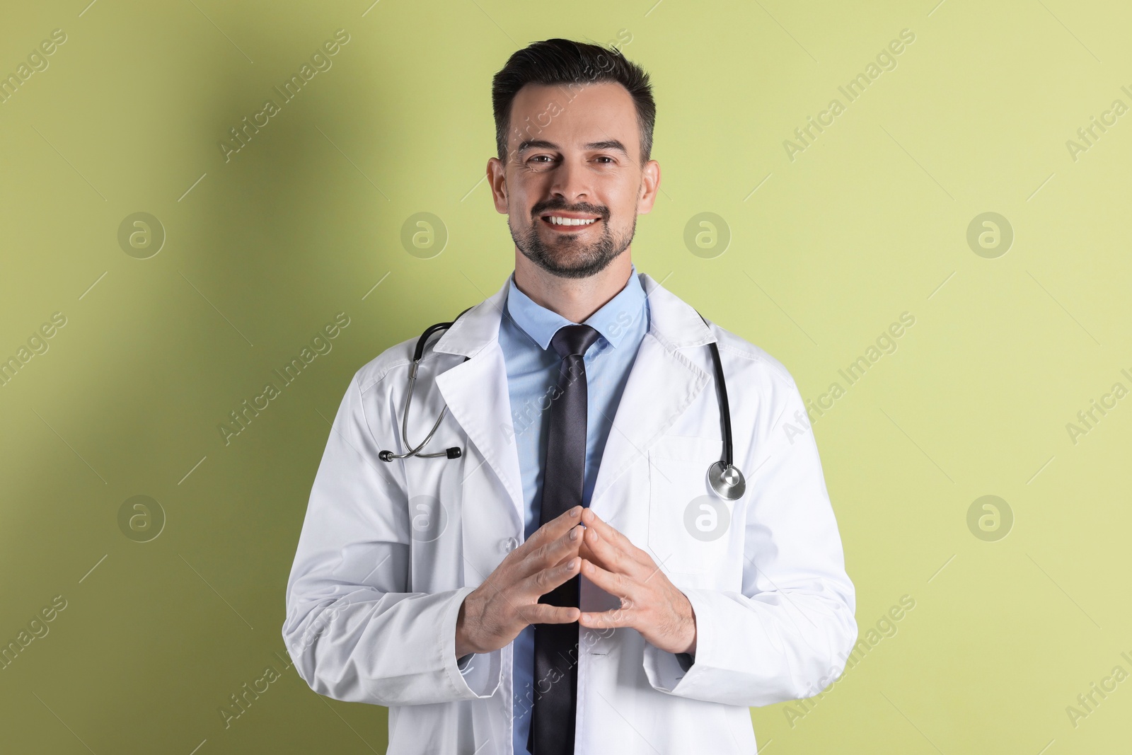 Photo of Smiling doctor with stethoscope on olive background