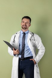 Photo of Smiling doctor with stethoscope and clipboard on olive background