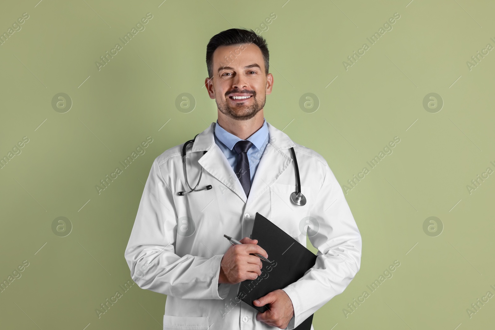 Photo of Smiling doctor with stethoscope and clipboard on olive background