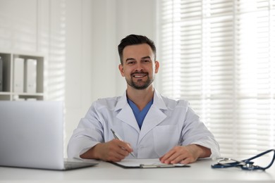 Smiling doctor working at table in clinic