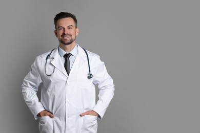 Photo of Smiling doctor with stethoscope on grey background, space for text