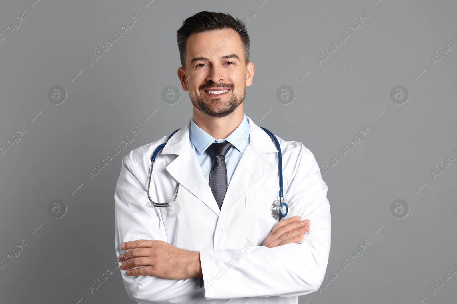 Photo of Smiling doctor with stethoscope on grey background