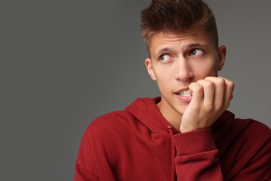 Portrait of scared young man on gray background, space for text