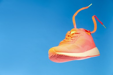 Photo of Stylish sneaker in air against light blue background, space for text