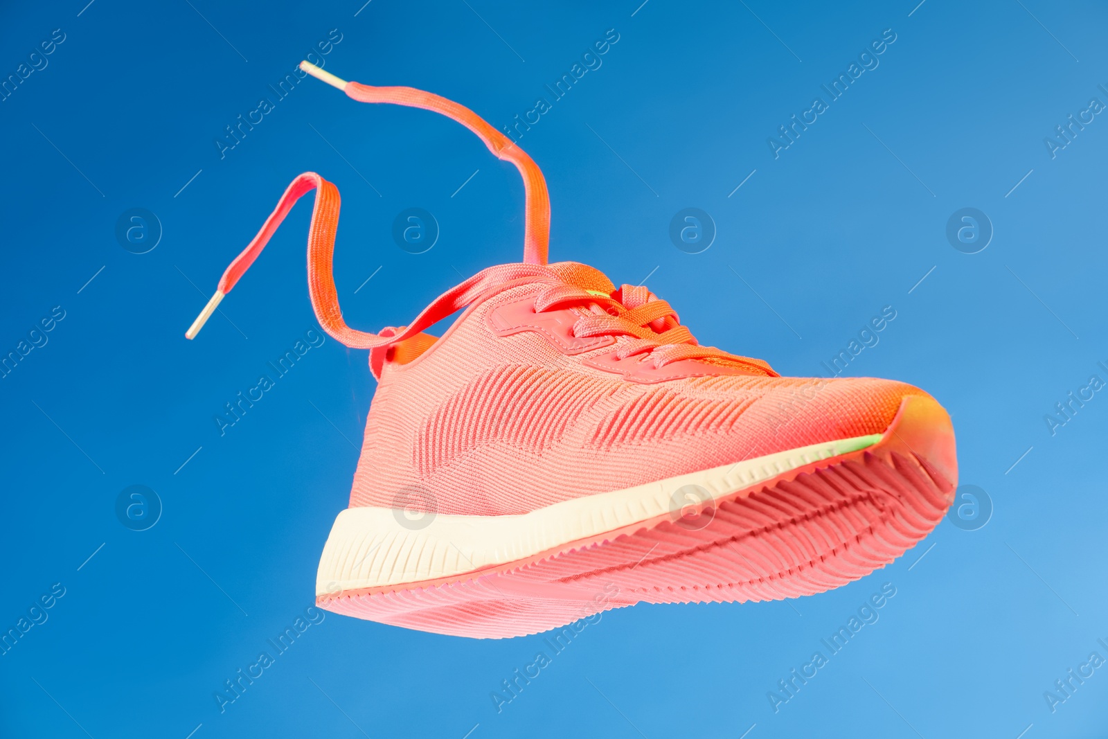 Photo of One stylish bright sneaker in air against light blue background