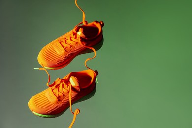 Pair of stylish sneakers in air against color background, space for text