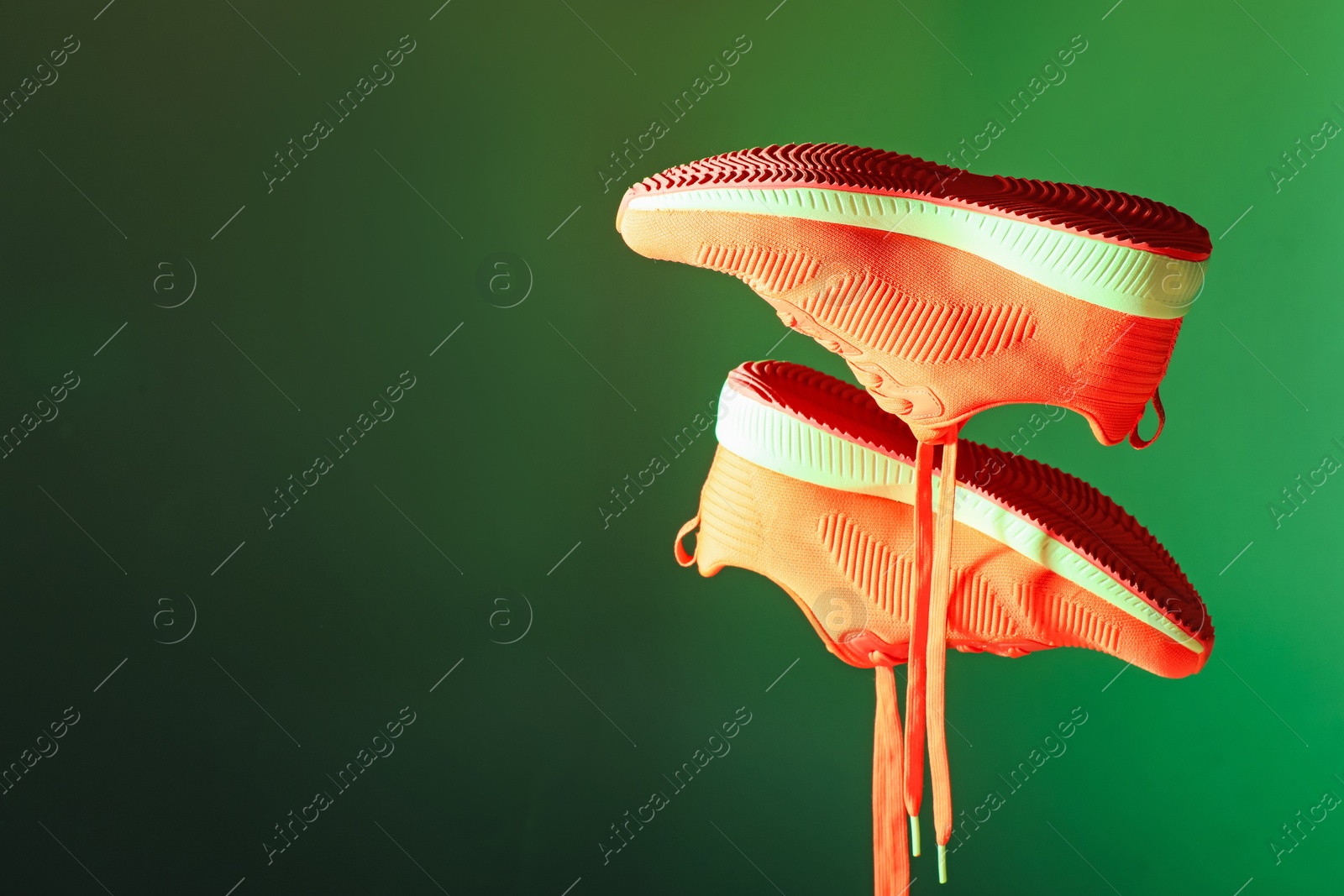 Photo of Pair of stylish sneakers in air against dark green background, space for text