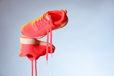 Photo of Pair of stylish sneakers in air against light grey background in neon lights, space for text