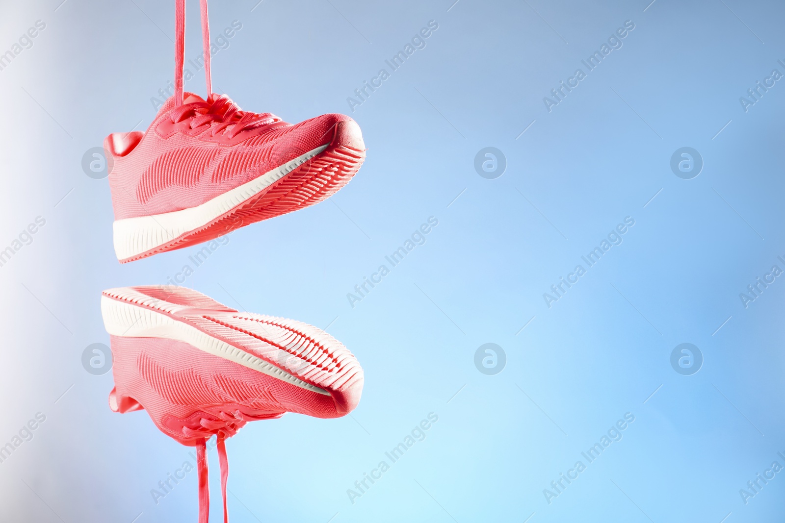 Photo of Pair of stylish sneakers in air against light blue background, space for text