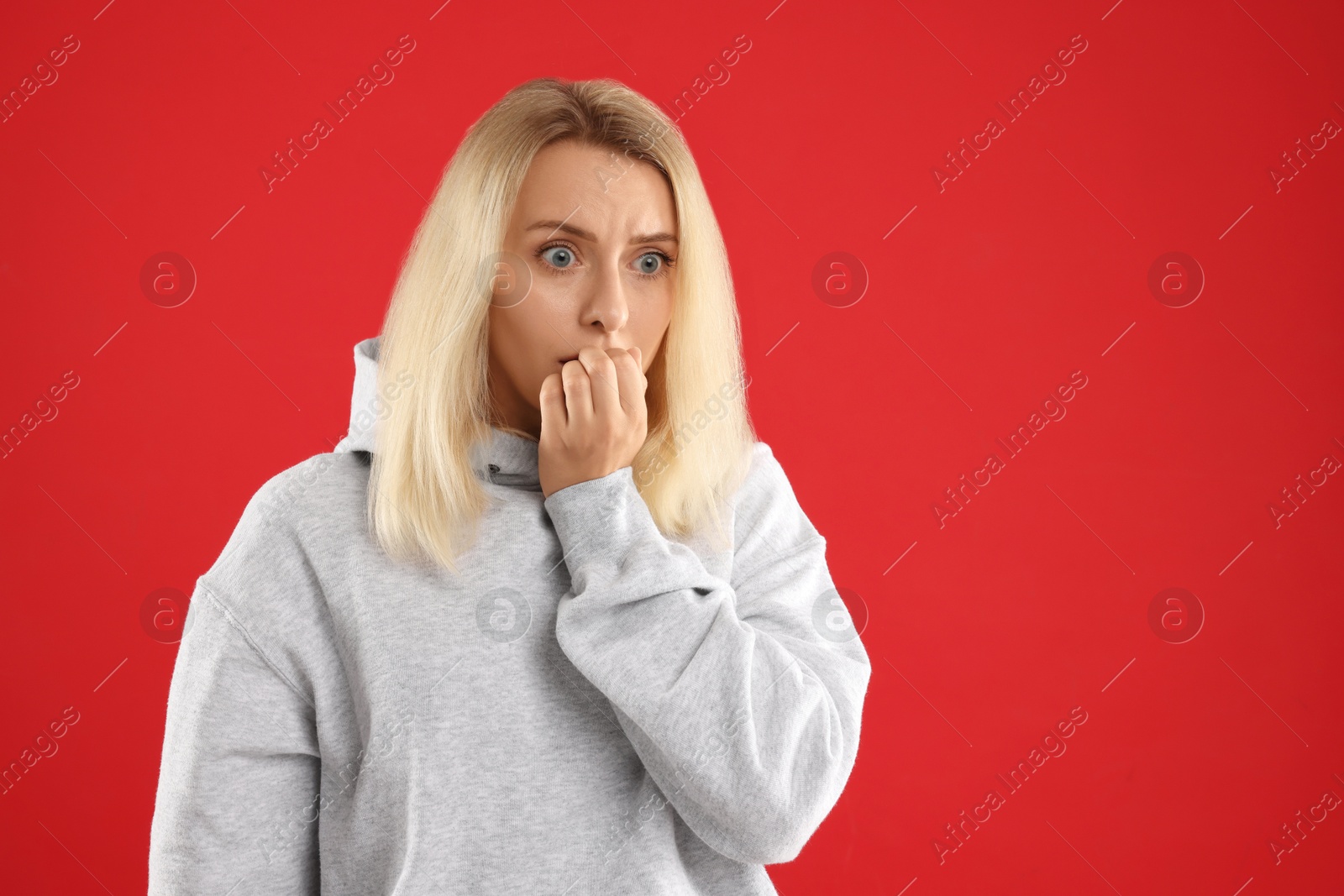 Photo of Portrait of scared woman on red background, space for text