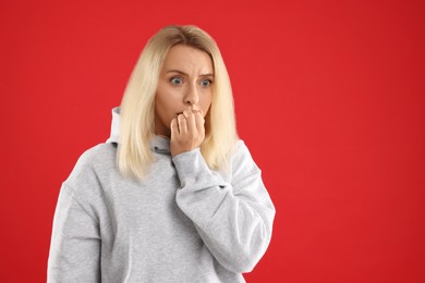 Photo of Portrait of scared woman on red background, space for text