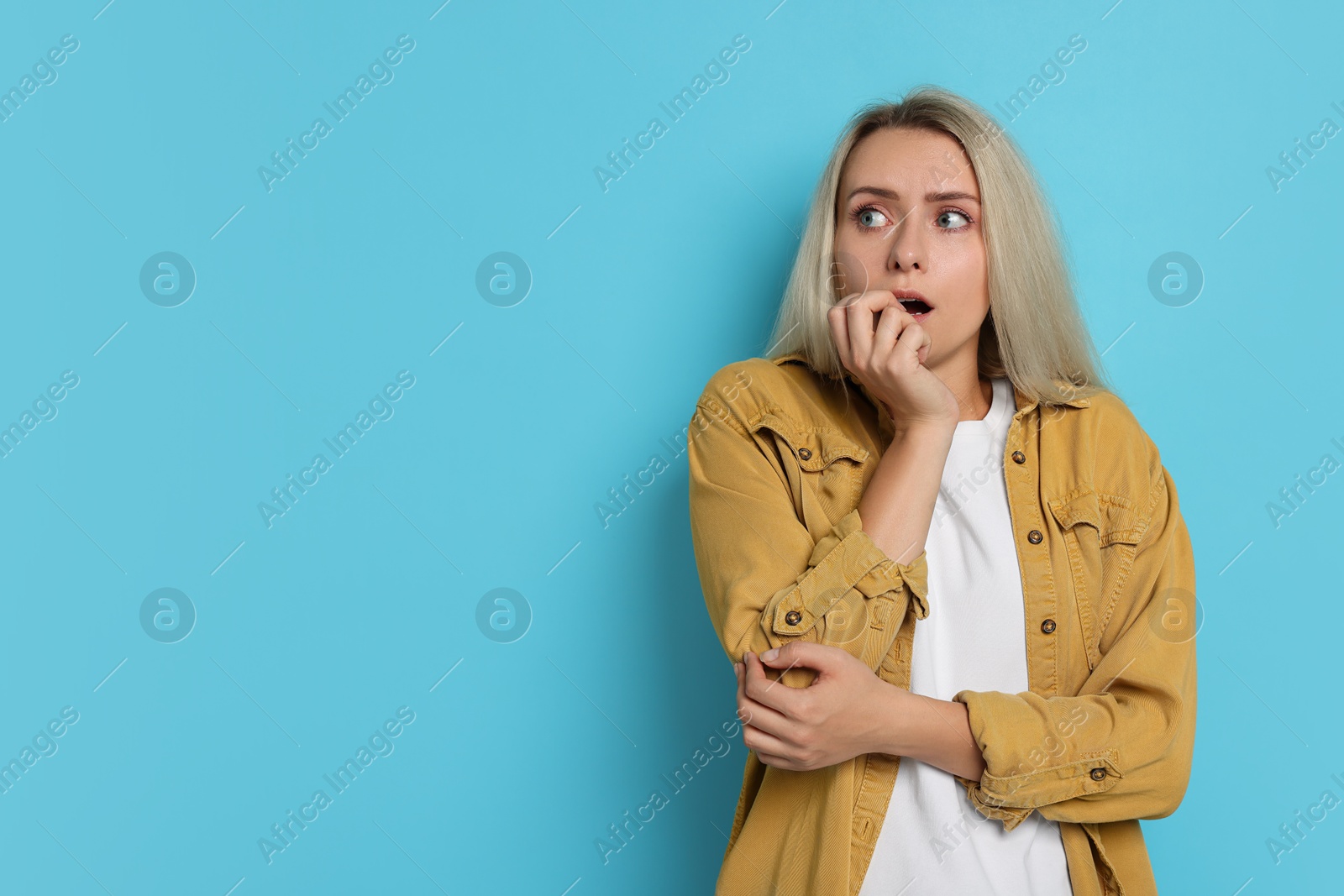 Photo of Portrait of scared woman on light blue background, space for text