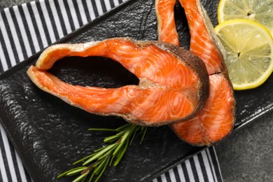 Photo of Tasty grilled salmon steaks, lemon and rosemary on table, top view